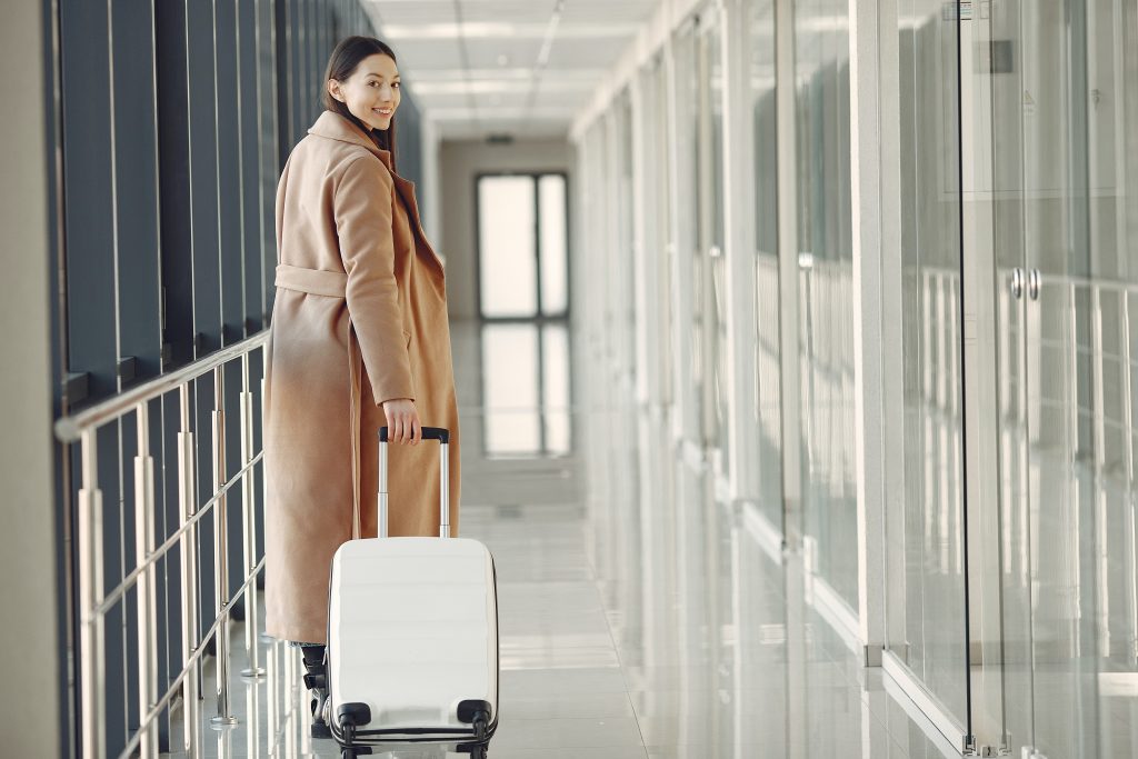 Business woman traveling at an airport with her suitcase